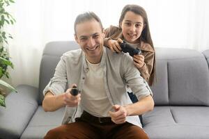 emocionado padre y hija jugando vídeo juego a hogar. foto