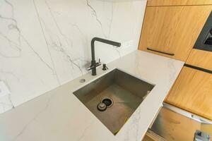 Black kitchen sink and Tap water in the kitchen. The interior of the kitchen room of the apartment. BuiltIn Appliances. Kitchen Appliance. Domestic Appliances. photo