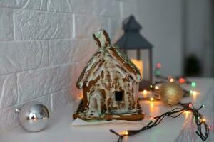 handmade gingerbread house with glaze standing on table with tablecloth and decorations. Holiday mood photo