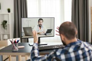 Nervous paralysed patient during online consultation with doctor. Young immobilized guy sitting at home in front of laptop, talking with his doctor about the process of rehabilitation on video call photo