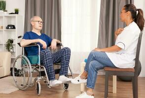 Ill man confessing to the doctor how he feels after the operation. Disabled disability old person with medical worker in nursing care home assistance, healthcare and medicine service photo