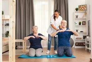 Senior couple doing physical therapy with doctor at home. Home assistance, physiotherapy, healthy lifestyle for old person, training and healthy lifestyle photo