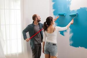 Husband helps his wife to paint the wall during home renovation. Apartment redecoration and home construction while renovating and improving. Repair and decorating. photo