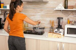 Cooking eggs in a pan for a healthy breakfast. Housewife getting helthy eggs and other ingredients from refrigerator in her kitchen. photo