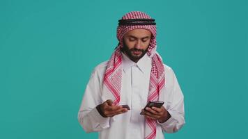 Arab person adding card numbers on website, doing online shopping spree on mall store retail app. Person paying for things on internet page, wearing traditional islamic attire with scarf. video