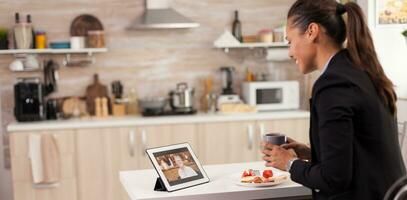 negocio mujer en un vídeo llamada con su madre durante desayuno. utilizando moderno en línea Internet web tecnología a charla vía cámara web video conferencia aplicación con parientes, familia, amigos y compañeros de trabajo foto