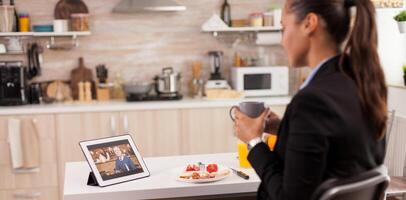 Freelancer discussing with old man online and drinking a cup of coffee. Using modern online internet web technology to chat via webcam videoconference app with relatives, family, friends and coworkers photo