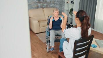 Invalid old woman in wheelchair doing rehab training with support from doctor. Disabled handicapped old person recovering professional help nurse, nursing retirement home treatment and rehabilitation photo