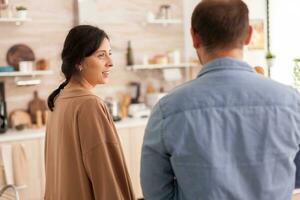 esposa mirando a marido en cocina llegando desde supermercado. sano contento relación estilo de vida para hombre y mujer, juntos compras productos foto