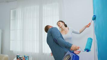 Cheerful young couple decorating apartment and dancing. Having fun and painting the walls. Apartment redecoration and home construction while renovating and improving. Repair and decorating. photo