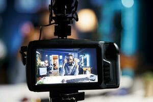 Focus on professional video production gear used for capturing footage of content creator in blurry background filming tech reviews for his internet channel, showcasing pair of headphones photo