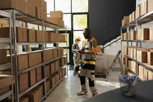 Stockroom worker having fun during warehouse inventory, listening music and dancing while analyzing products checklist. Employee with protective overall preparing customers orders photo