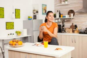 Woman drinking hot coffee to wake up in the morning. Lady ejoying a cup of coffee in the morning. Happy housewife relaxing and spoiling herself with a healthy meal alone photo