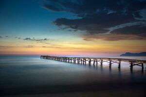 de madera muelle en el este costa de mallorca a amanecer foto