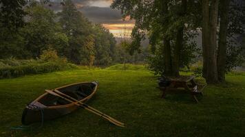 Canoe on a green meadow at sunset photo