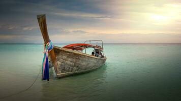 cola larga barco en un playa en Tailandia a puesta de sol foto