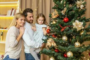 Christmas and new year family decorate tree, man woman and child daughter at home together in living room for new year smile and rejoice, happy family holidays. photo