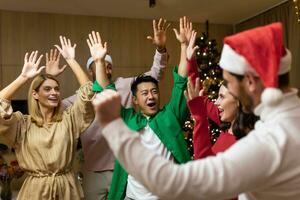 New Year holiday party. Young beautiful interracial people, men and women, dancing and having fun at home near the Christmas tree. photo