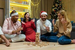 New year party, various friends at home on floor playing game, men and women smiling and happy together for christmas spend time. photo