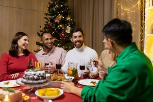 Friends celebrate Christmas eve or New Year holiday paty ,together sitting at the table. Feast at home group ,of multi ethnic festive christmas dinner. happy cheerful people clink wine glasses laugh photo