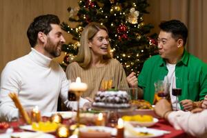 Friends celebrate Christmas eve or New Year holiday paty together sitting at the table. Feast at home group of multi ethnic festive christmas dinner. happy cheerful people. photo