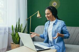 Happy hispanic woman at home working remotely from home, customer service online store tech support worker using headset for video call and customer consultation remotely from home. photo