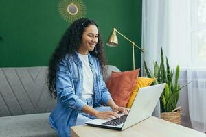 Happy hispanic woman at home working remotely from home, customer service online store tech support worker using headset for video call and customer consultation remotely from home. photo