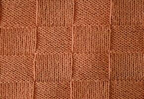 Texture of smooth knitted sweater with pattern. Top view, close-up. Handmade knitting wool or cotton fabric texture. Unusual abstract knitted chess pattern background texture. photo