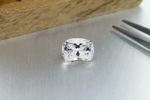 macro mineral faceted stone Morganite with tweezers on a gray background photo