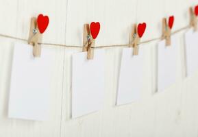 white pieces of paper on clothespins with a heart on a wooden background photo