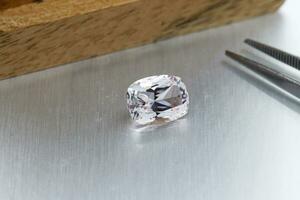 macro mineral faceted stone Morganite with tweezers on a gray background photo