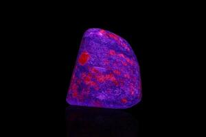 macro mineral stone ruby under ultraviolet light on a black background photo