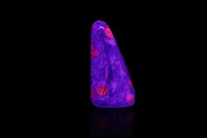 macro mineral stone ruby under ultraviolet light on a black background photo