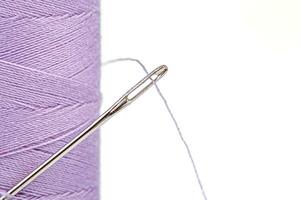 Macro skein of thread purple colors with a needle on a white background photo