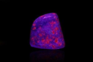 macro mineral stone ruby under ultraviolet light on a black background photo