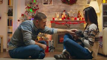 hermoso joven hombre jugando con gato mientras celebrando Navidad con su esposa en frente de chimenea. foto