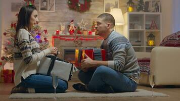 Cheerful couple giving each other gifts on christmas day in front of fireplace. photo