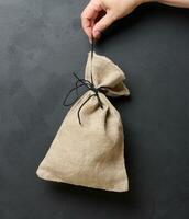 A woman's hand holds a canvas bag on a black background, the concept of a subsidy photo