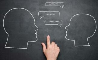 Chalk drawn silhouettes of a man and a woman, talking and a hand between them. photo