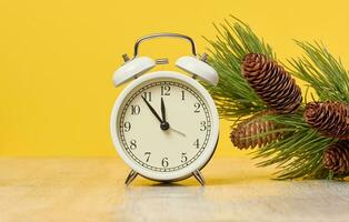 Round alarm clock, time is five minutes to twelve. Yellow background photo