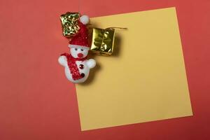 snowman and gift box on a yellow sheet of paper on a red background photo