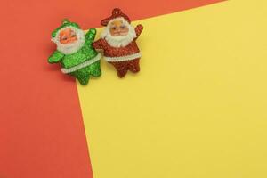 Two Santa Clauses and Christmas Elf on yellow and red background with copy space photo