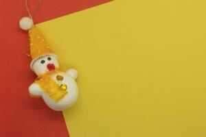 Snowman and Christmas decoration on yellow and red background with copy space photo