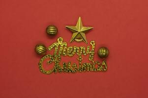 Merry Christmas lettering greeting card with gold star and baubles on red background photo