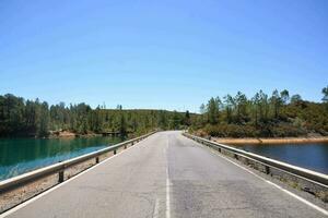 un largo puente con arboles y agua en el lado foto