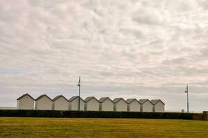 a row of white huts on a grassy field photo