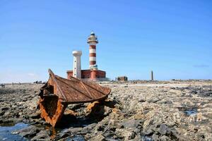 rusty metal on the rocks near a lighthouse photo