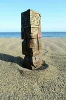 a wooden tiki statue on the beach photo