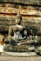 a buddha statue is sitting on a stone wall photo