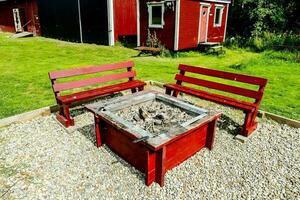 red benches and fire pit in front of a red house photo